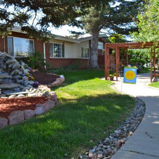 A beautifully landscaped front yard featuring a rock garden, lush green grass, and a welcoming pathway.