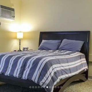 A cozy bedroom with a neatly made bed featuring striped bedding and a warm bedside lamp.