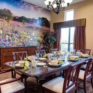 A beautifully set dining room with a long table, elegant chairs, and a scenic mural on the wall.