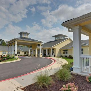 A well-maintained building with a covered entrance and landscaped surroundings under a partly cloudy sky.