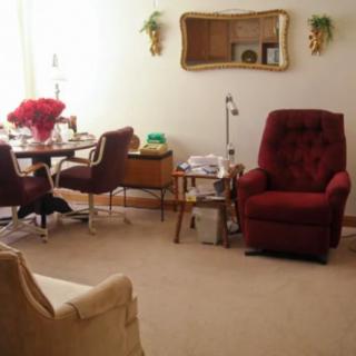 A cozy living room with a red armchair and dining table set.