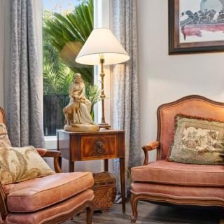 A cozy living room corner featuring vintage armchairs, a side table with a decorative lamp, and elegant cushions.