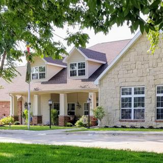 A suburban residential house with a well-maintained lawn and trees in the foreground.