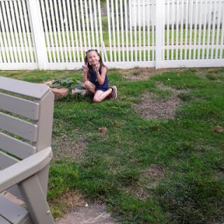 A girl sitting on the grass, enjoying her time outdoors.