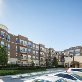 A modern apartment building with a parking lot in front.
