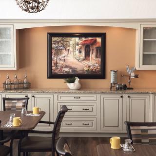 A cozy kitchen with elegant cabinets and a painting above the counter.