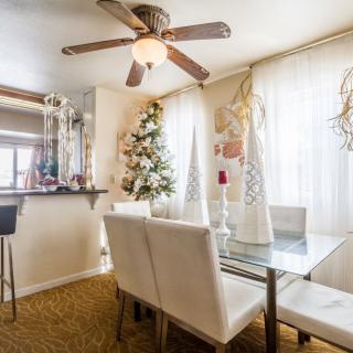 A modern dining room with a glass table and white chairs, tastefully decorated and lit by natural light.
