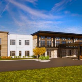 A modern building with a sleek design under a clear blue sky, surrounded by landscaped greenery.