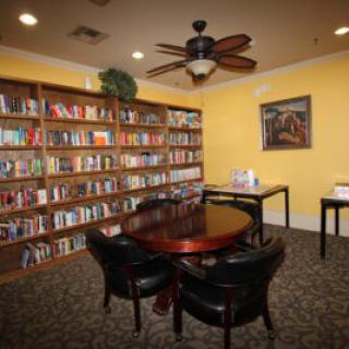 A cozy library reading room with bookshelves and a round table.