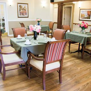 A well-arranged dining room with tables and chairs, featuring floral decorations and a cozy atmosphere.