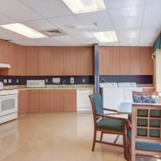 A well-lit kitchen and dining area featuring wooden cabinets, a dining table with chairs, and various appliances.