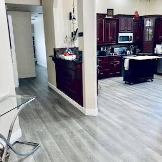 A spacious kitchen and living area featuring modern wooden cabinetry and stylish gray flooring.