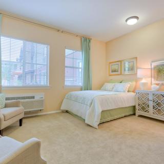 A cozy and well-lit bedroom with a bed, armchair, and stylish decor.