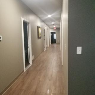 A long indoor hallway with several doors and modern lighting.