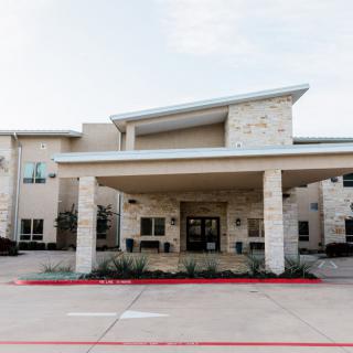 A modern building entrance with a stone facade and covered drop-off area.