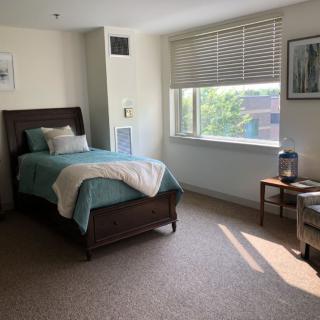 A cozy bedroom with a single bed, window, and minimalist decor.