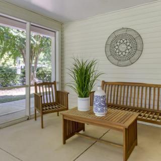 A cozy sunroom with wooden furniture and decorative accents.