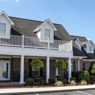 A large house with a front porch and balcony under a clear blue sky.