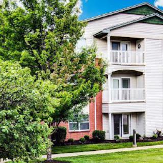 A residential apartment building surrounded by trees on a sunny day.