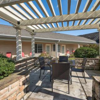 A sunny patio area featuring a pergola and outdoor seating.