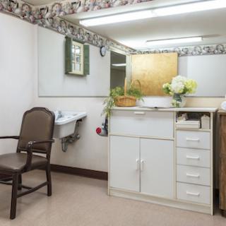 A well-lit bathroom with a vanity, mirror, and decorative flowers.