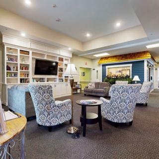 A modern and cozy living room with patterned chairs, a sofa, bookshelves, and a television.