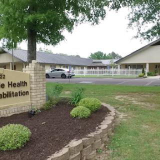 Exterior view of a health rehabilitation facility, featuring landscaped grounds and clear signage.