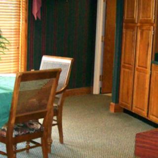 A cozy dining room with wooden chairs and a table, featuring a large wooden cabinet and carpet flooring.