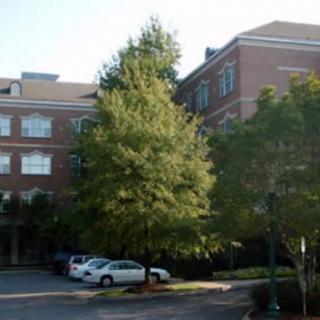 A brick building with adjacent parking lot and trees.