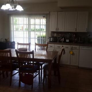 A kitchen and dining area with a wooden table, chairs, and white cabinets next to a large window.