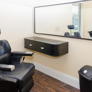 A modern hair salon with a barber chair and large mirror.