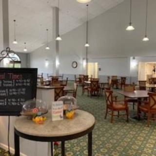 A spacious dining area with neatly arranged tables and chairs, featuring a menu board and subtle lighting.