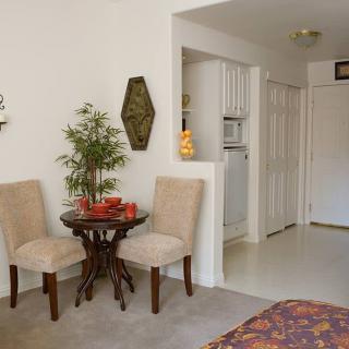 A cozy living room corner with a small dining table and two chairs, adorned with decorative elements and a potted plant.
