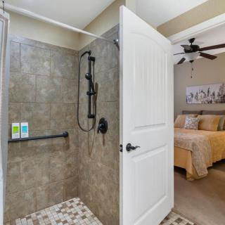 A cozy bedroom adjacent to a modern tiled shower area.
