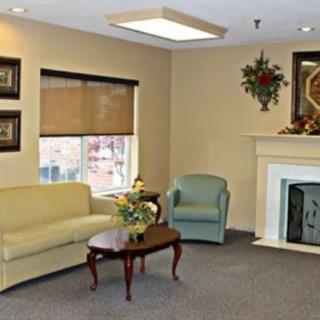 A cozy living room with a sofa, armchair, and fireplace, adorned with artwork and decor.