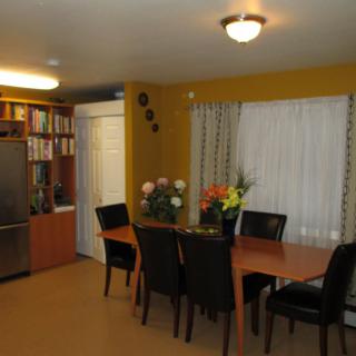 A cozy dining room with a wooden table and black chairs, adorned with floral arrangements.