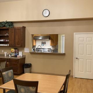 A kitchen and dining area with a wall clock, wooden cabinets, and a table with chairs.