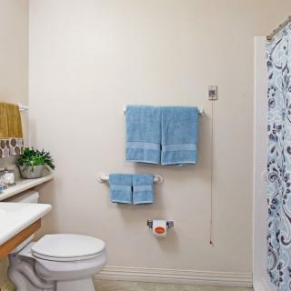 A clean and organized bathroom with blue towels and a decorative shower curtain.