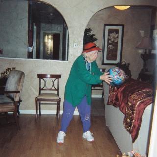 A person in casual clothing is playing with a ball indoors, in a living room setting.