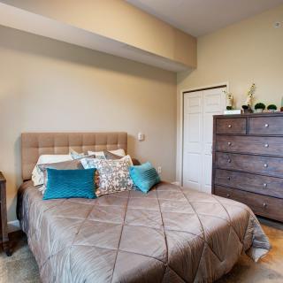 A cozy bedroom with a neatly made bed and a dresser.