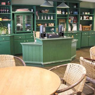 A cozy cafe interior with green cabinets and a seating area.