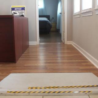 The image shows a hallway with hardwood flooring leading to a bedroom and office space.