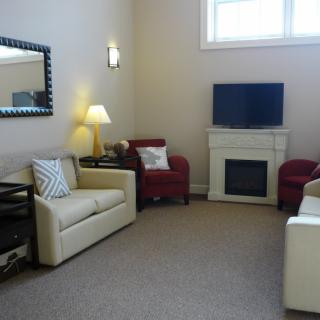 A cozy living room with sofas and armchairs arranged around a fireplace and television.