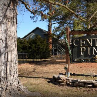 A wooden sign for 'Center Pines' set amongst trees and a building in the background.