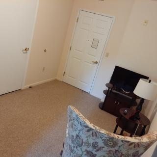 A cozy living room with a chair, television, and lamp near the door.