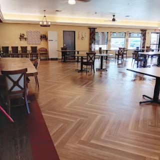 A spacious and well-lit dining area with wooden floors and neatly arranged tables and chairs.