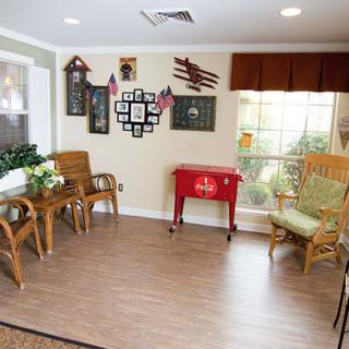 A cozy living room with wicker furniture, wall decorations, and a red cooler.