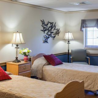 A cozy bedroom with twin beds, decorative lamps, and wall art.