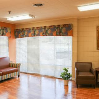 A well-lit living room with a couch, chairs, and large windows allowing natural light.
