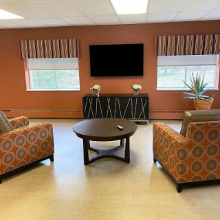 A cozy living room setup with patterned chairs, a coffee table, and a television on the wall.